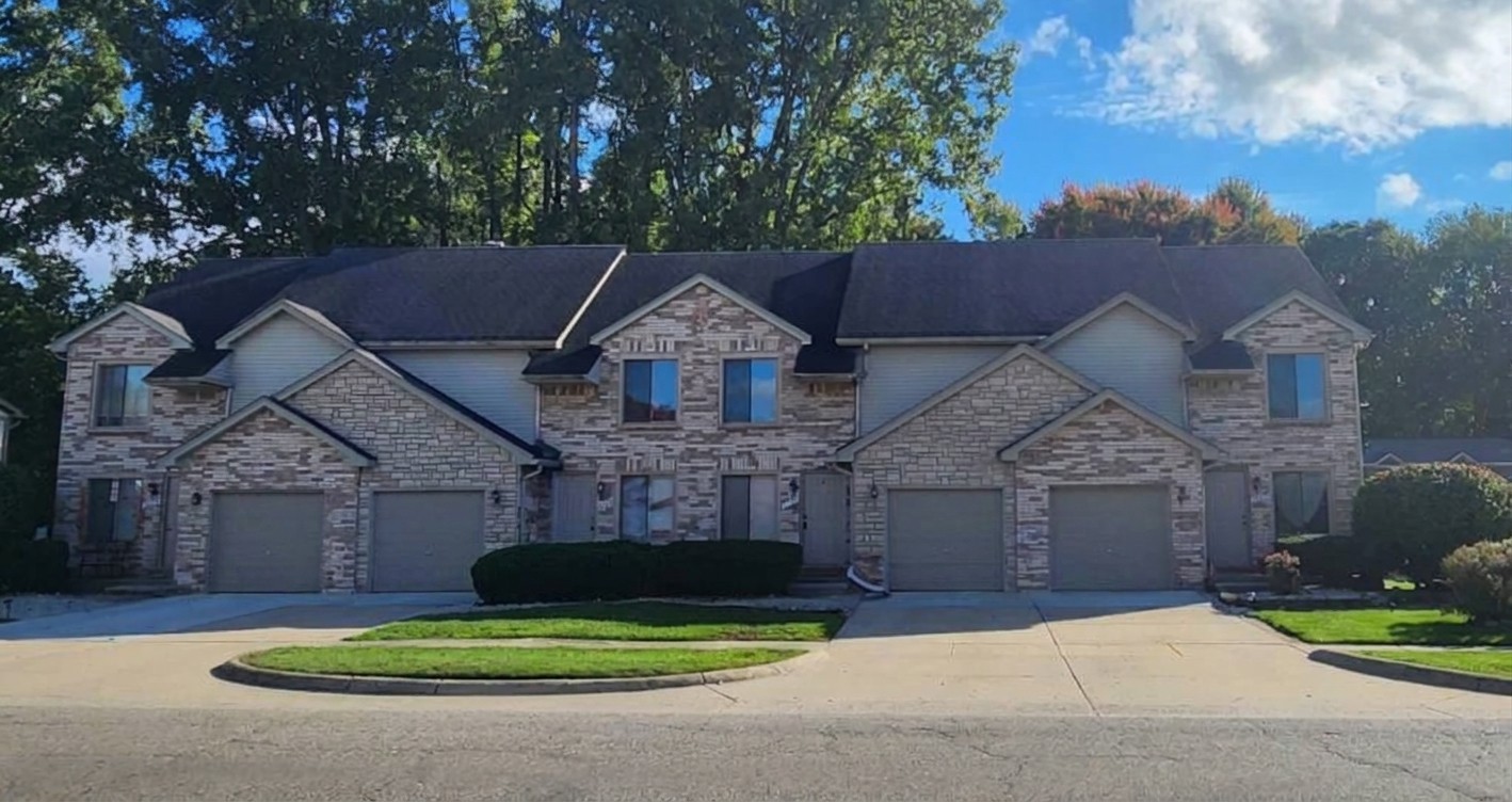 Brick and stone fourplex townhouses with attached garages on Annsbury Drive, Shelby Township