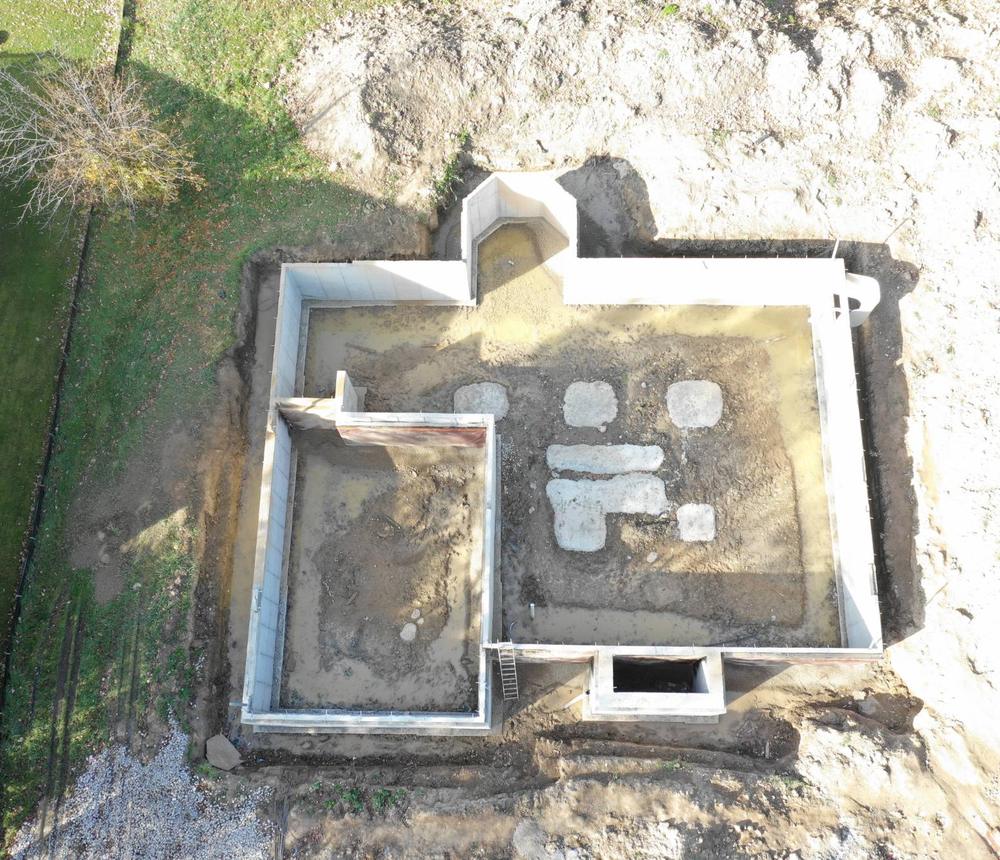 Aerial view of a new home foundation with poured walls before framing