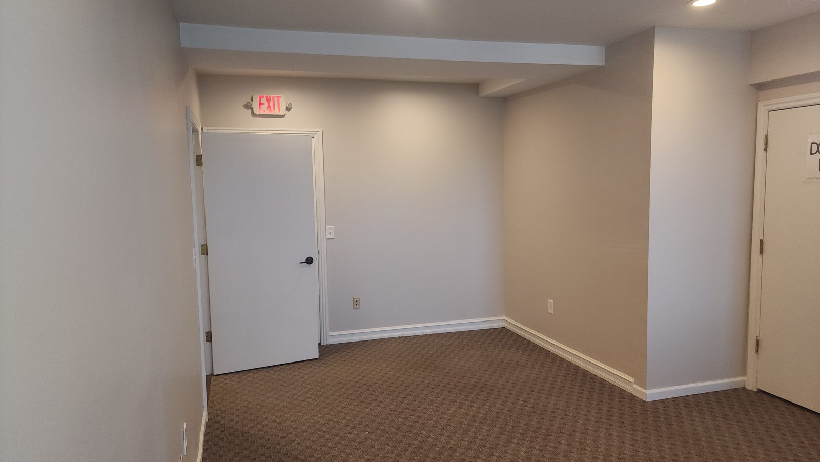 Carpeted private room in Suite 101 with an exit door